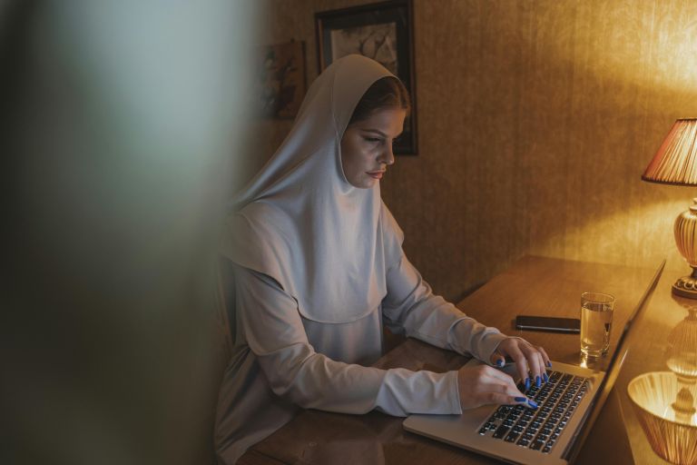 A woman in scarf working on a laptop