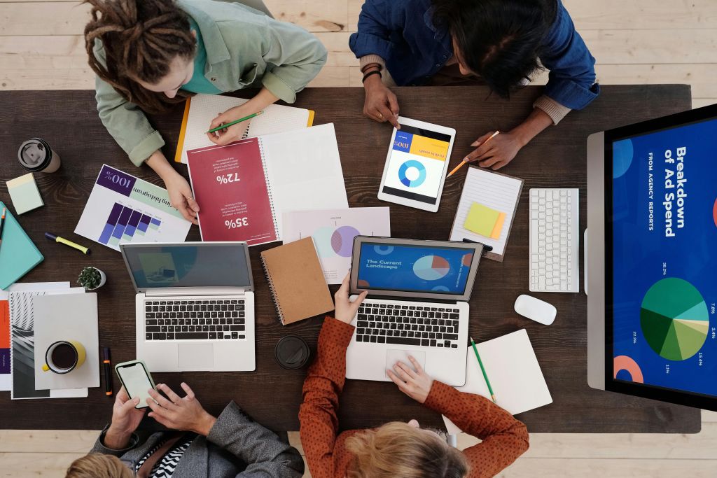 Photo of co-workers working on their laptops sitting beside the table